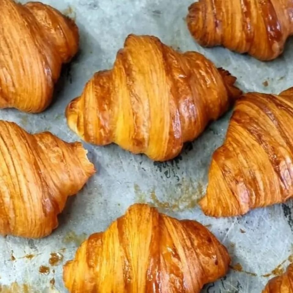 Golden-brown flaky croissants arranged on a baking tray.