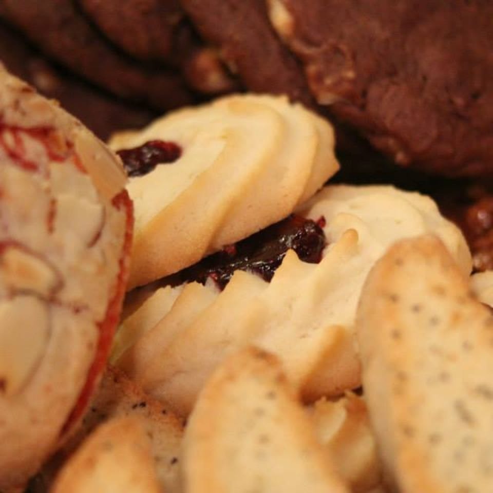 Close-up assortment of pastries, including almond-topped cookies, fruit-filled biscuits, chocolate cookies, and crumbly baked treats.