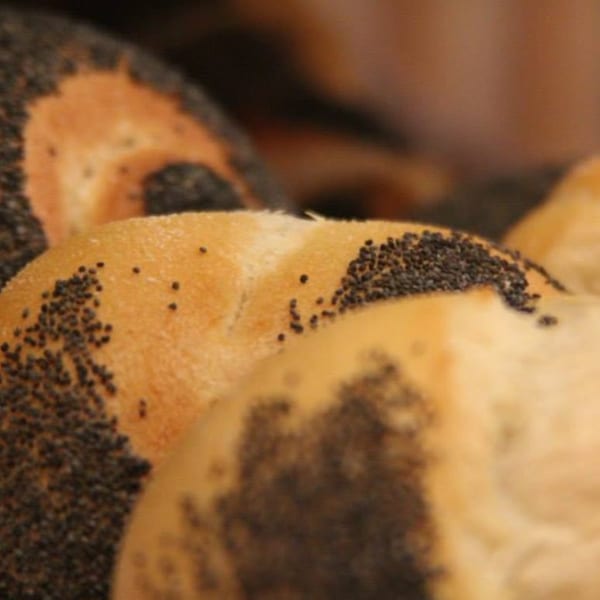 Close-up of several freshly baked bread rolls, some topped with poppy seeds.