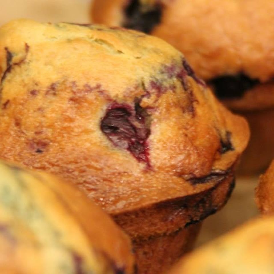 Close-up of golden blueberry muffins, with several pastries arranged closely together.