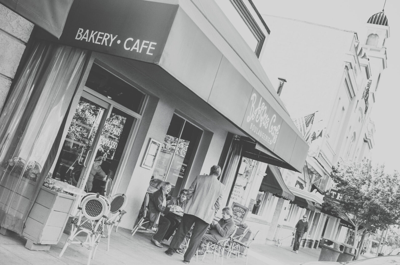 A black and white photo of people outside a bakery cafe.