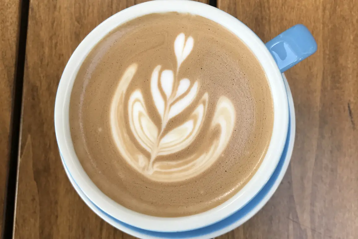 A cup of coffee with a leaf design on it.